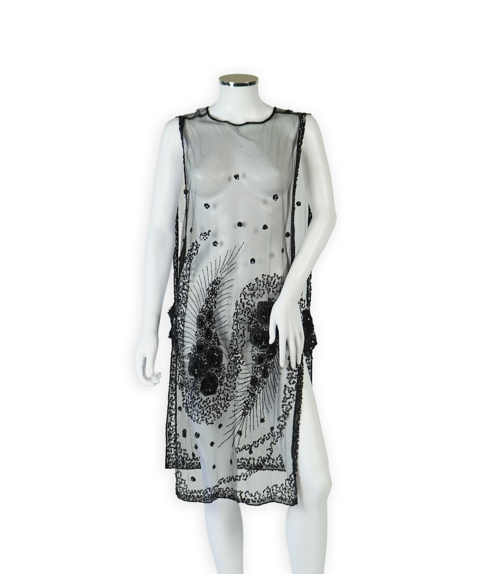 A 1920's black sequin on net tabard, with floral decoration and two side sequinned straps. Length 97cm. Condition - a few sequins have detached but are in a bag for re-attaching.